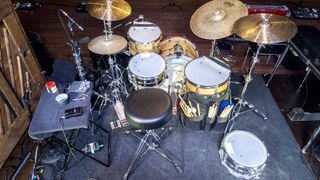 Looking at a yellow drum kit from behind on stage with a drum stool in the foreground