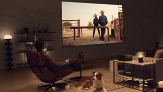 El televisor LG M3 OLED en una sala de estar con un hombre y un perro mirando la pantalla