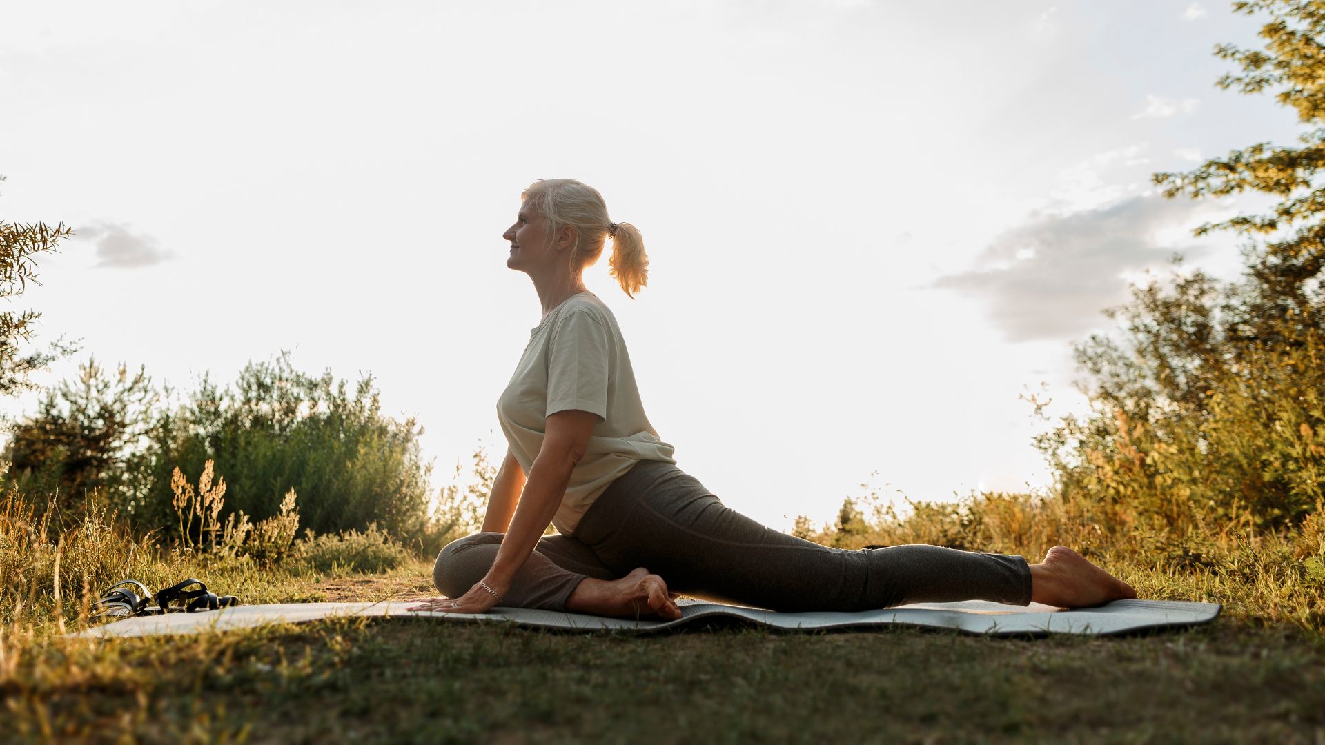 Woman doing yoga on mat in garden in the sunshine