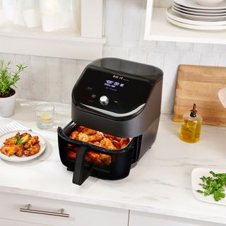 Air fryer on kitchen worktop next to cooked food