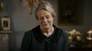 Dame Maggie Smith smiling in a sitting room in Downton Abbey: A New Era.