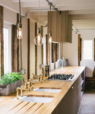 A wooden kitchen designed by deVOL with vintage lighting