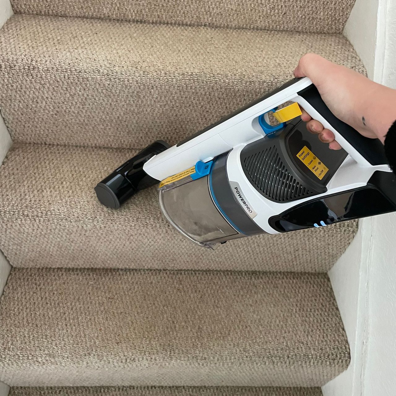 Shark PowerPro Pet Cordless Stick Vacuum in handheld mode, cleaning cream carpeted stairs
