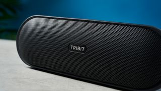 The Tribit XSound Plus 2 on a stone surface against a blue background