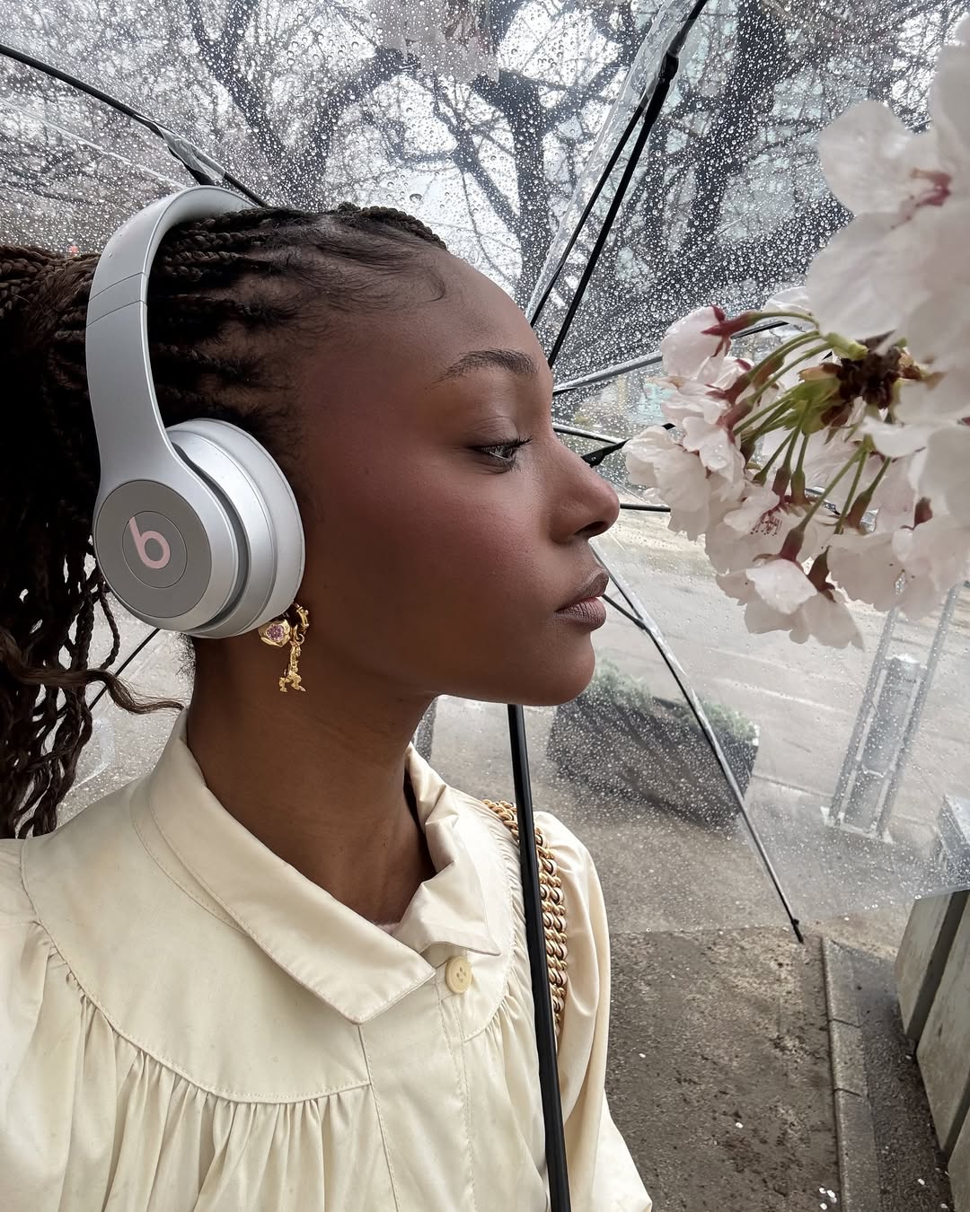 Camri Hewie poses on a rainy day in Tokyo, Japan with cherry blossoms
