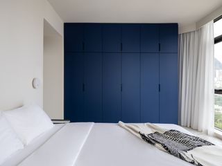 bedroom with white bed and walls and blue fitted wardrobes