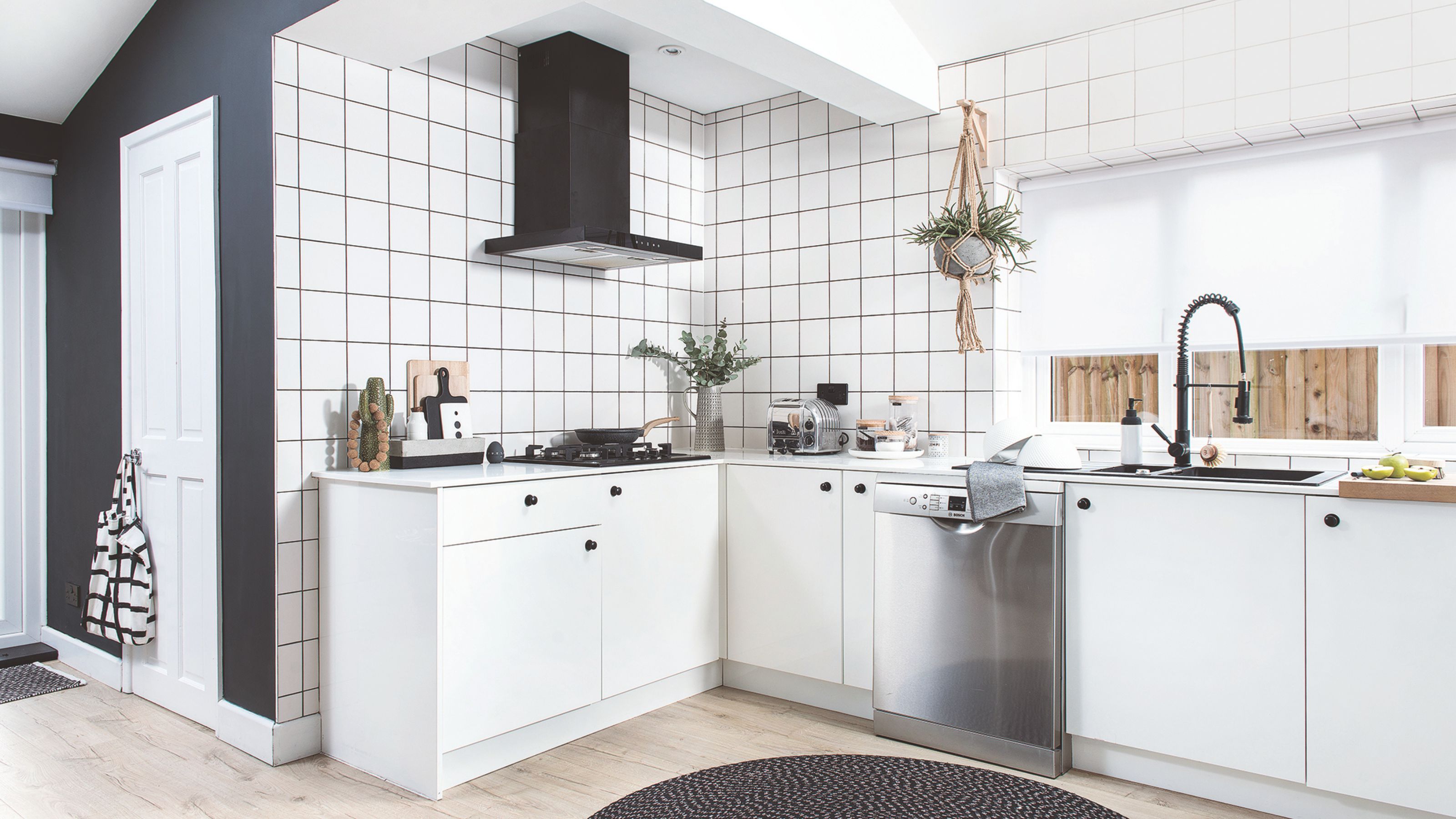 Black and white L-shaped kitchen with square tiles and black extractor fan