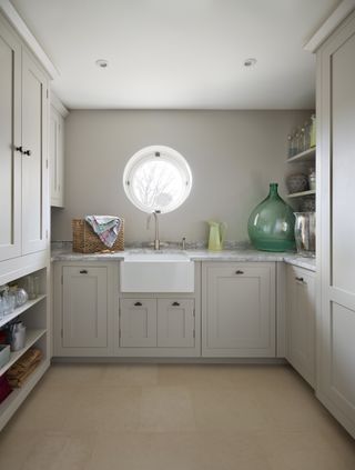 A soft grey utility room featuring low level shelving for storage