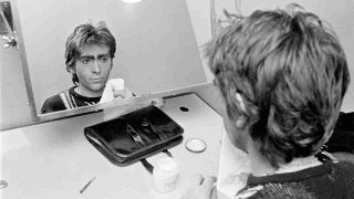 Genesis’s Peter Gabriel apply make up backstage before a gig in in 1975