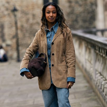 Attendee at spring summer 2025 fashion week wearing suede jacket and bag