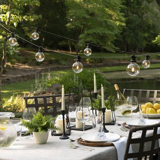 festoon lights over an outdoor dining table by Lights.com
