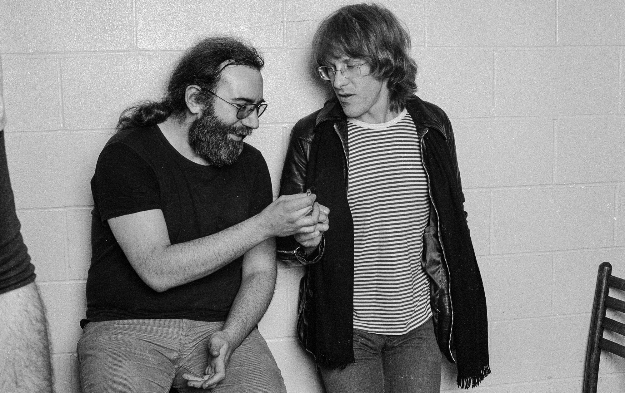 Guitarists Jerry Garcia of the Grateful Dead takes a joint from Paul Kantner of Jefferson Airplane/Starship, backstage at the Old Waldorf theater.