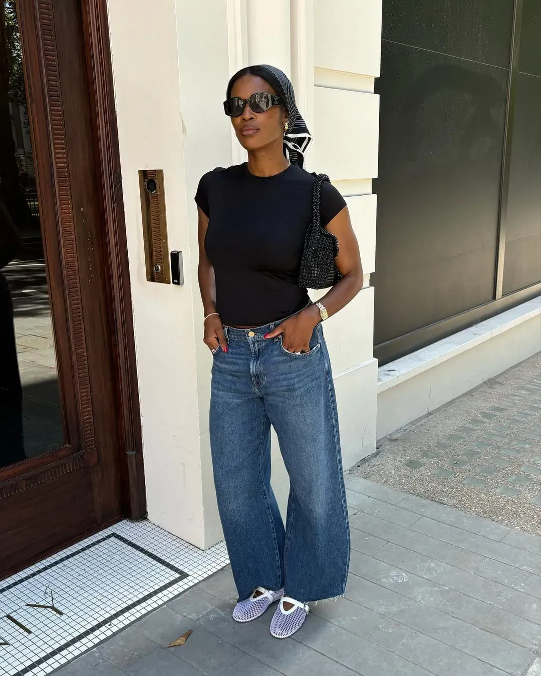 A woman wears white mesh ballet flats with jeans and a black top.