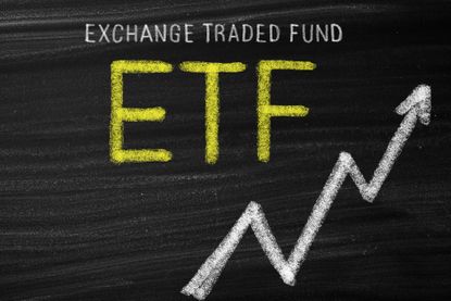 ETF and exchange-traded fund written on chalkboard in yellow with white arrow going higher