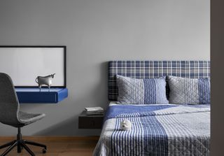 A bedroom with gray walls and blue bedding in stripes