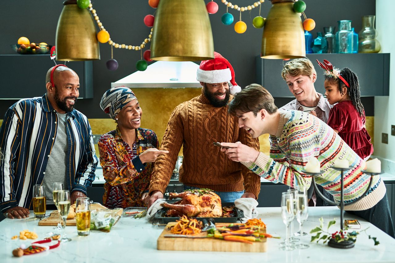 Multi ethnic family gathering for Christmas dinner, freshly cooked turkey resting on baking tray, family looking and smiling