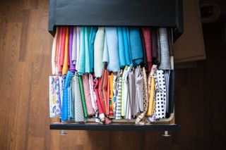 Fabric samples of colorful textile in a chest of drawers. Organization of a workplace of seamstress.