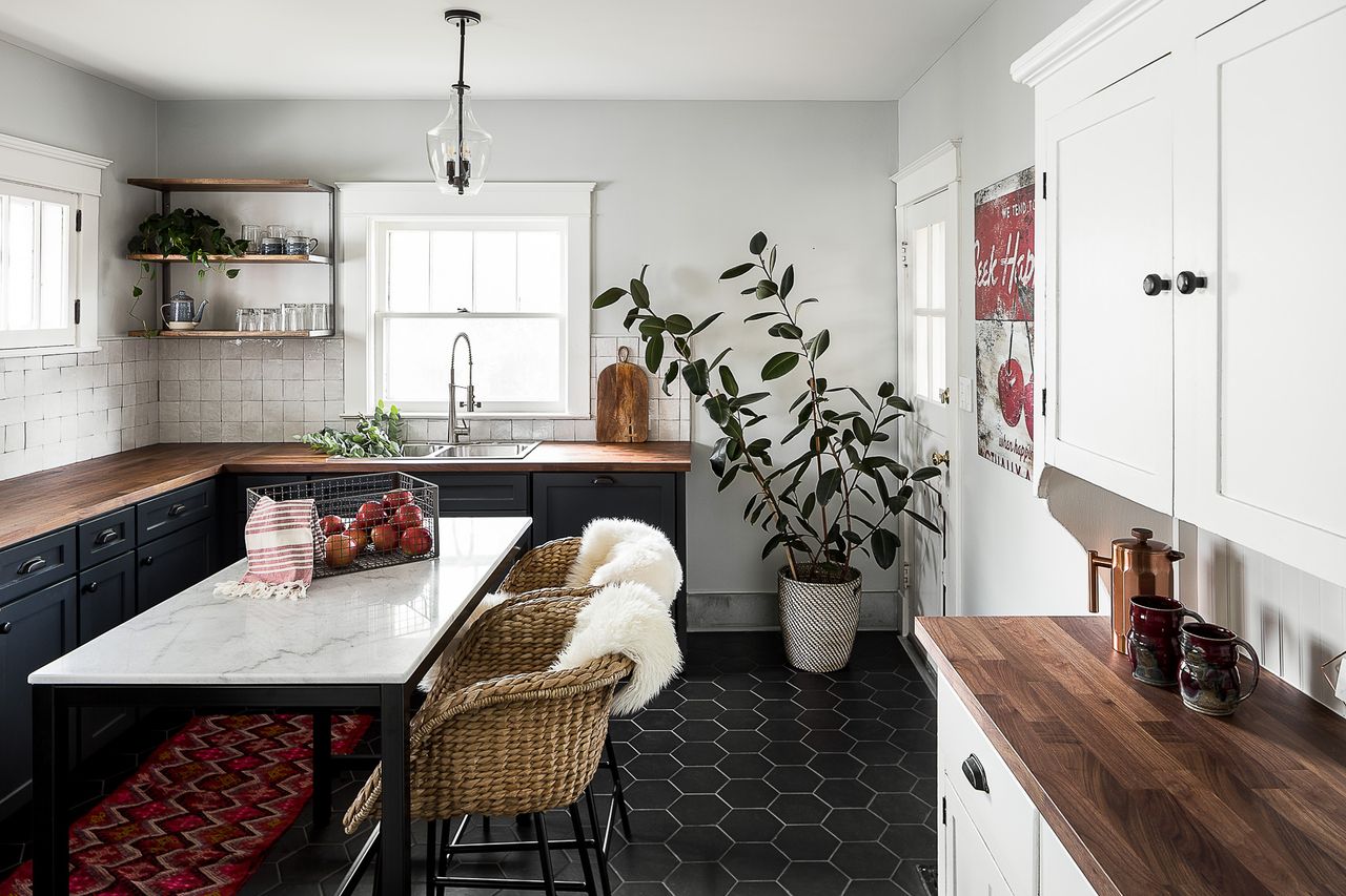 A kitchen with dark flooring and white walls, with a marble island