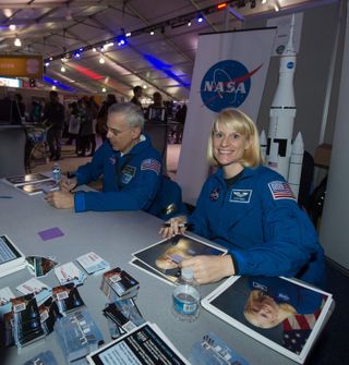 NASA Astronaut Kate Rubins smiles for the camera while signing autographs at the NASA booth set up on the National Mall as part of the National Day of Service, Saturday, Jan. 19, 2013.