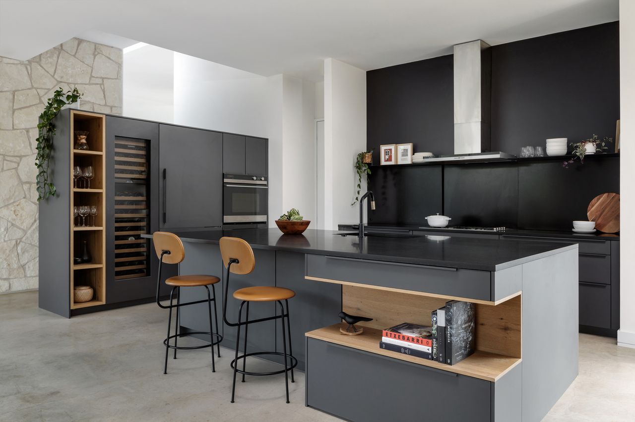 dark kitchen with black counter, timber accents, timber bar stools, wine fridge, integrated appliances, and gray flooring