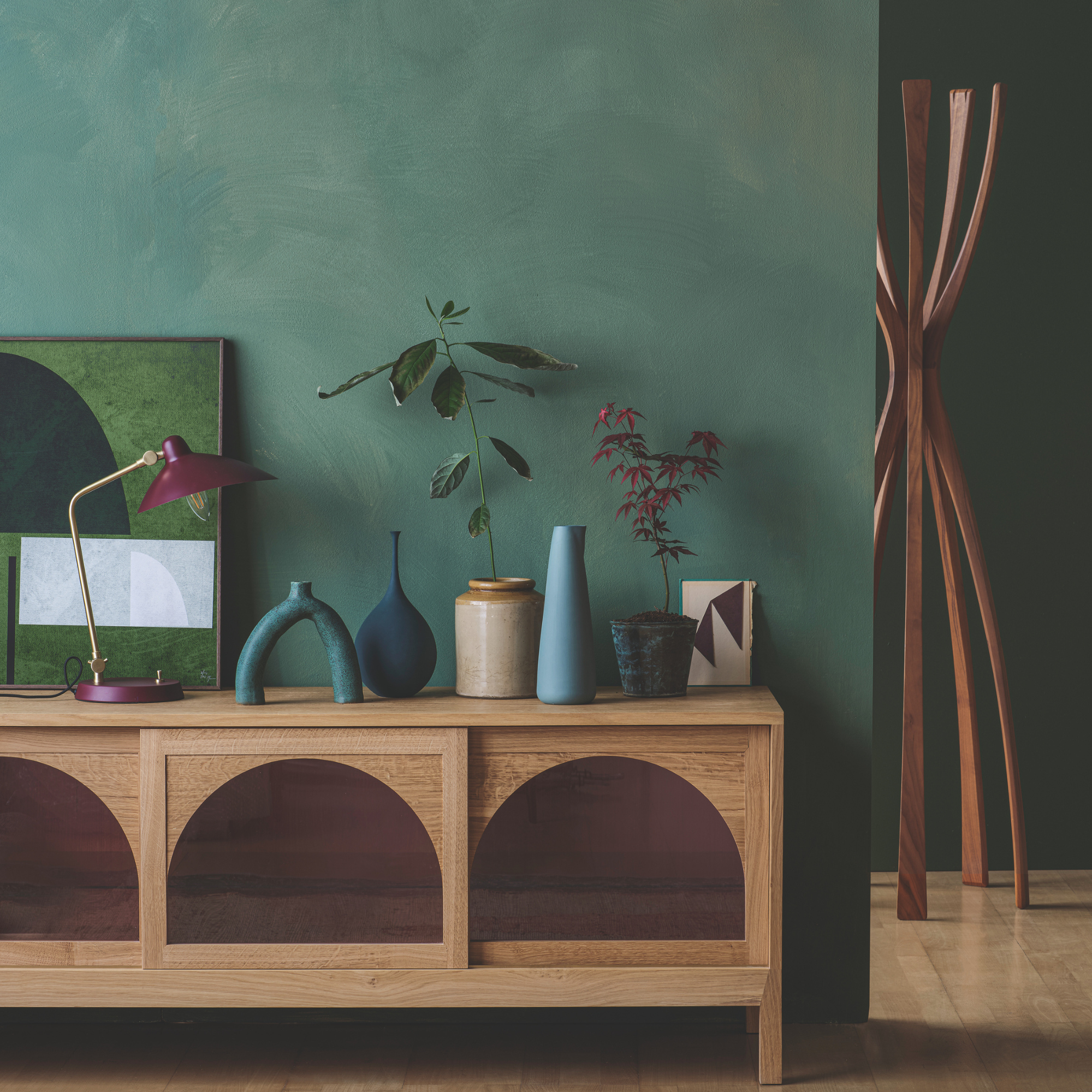 Wooden sideboard with blue ornaments and a red and gold lamp.