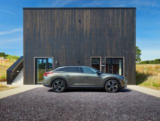 Citroën C5 X in front of a wooden house