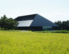 Exterior of the Kengo Kuma designed IWA sake brewery set among green paddy fields