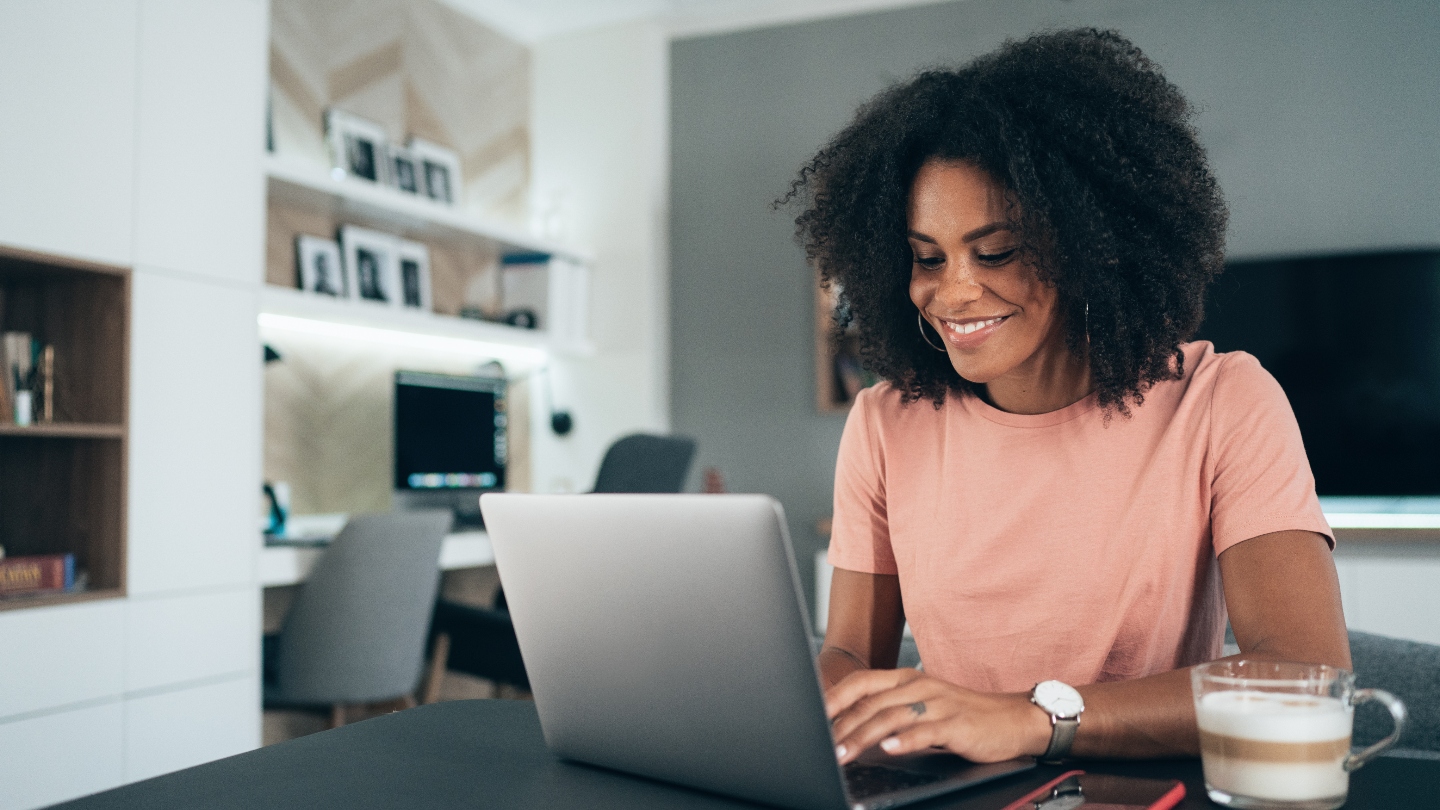 Woman sitting at table typing at computer and smiling