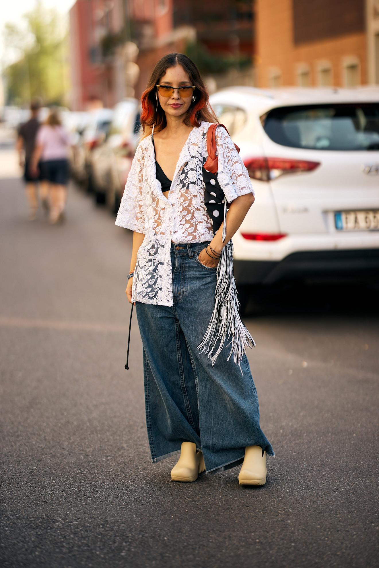 a woman in a white lace shirt and jeans on the street in milan