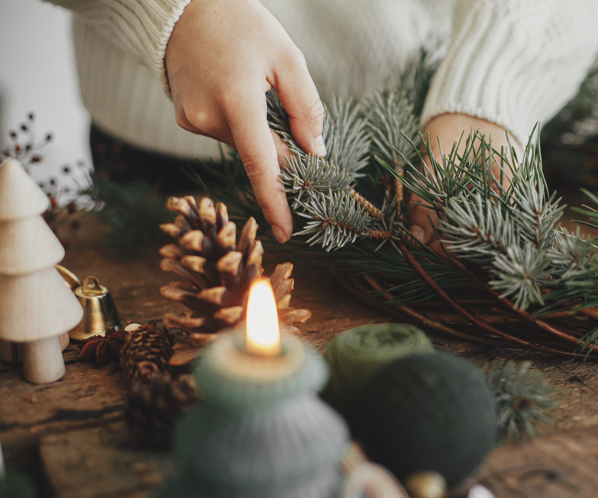Hands making a holiday wreath from pine and spruce on a willow base