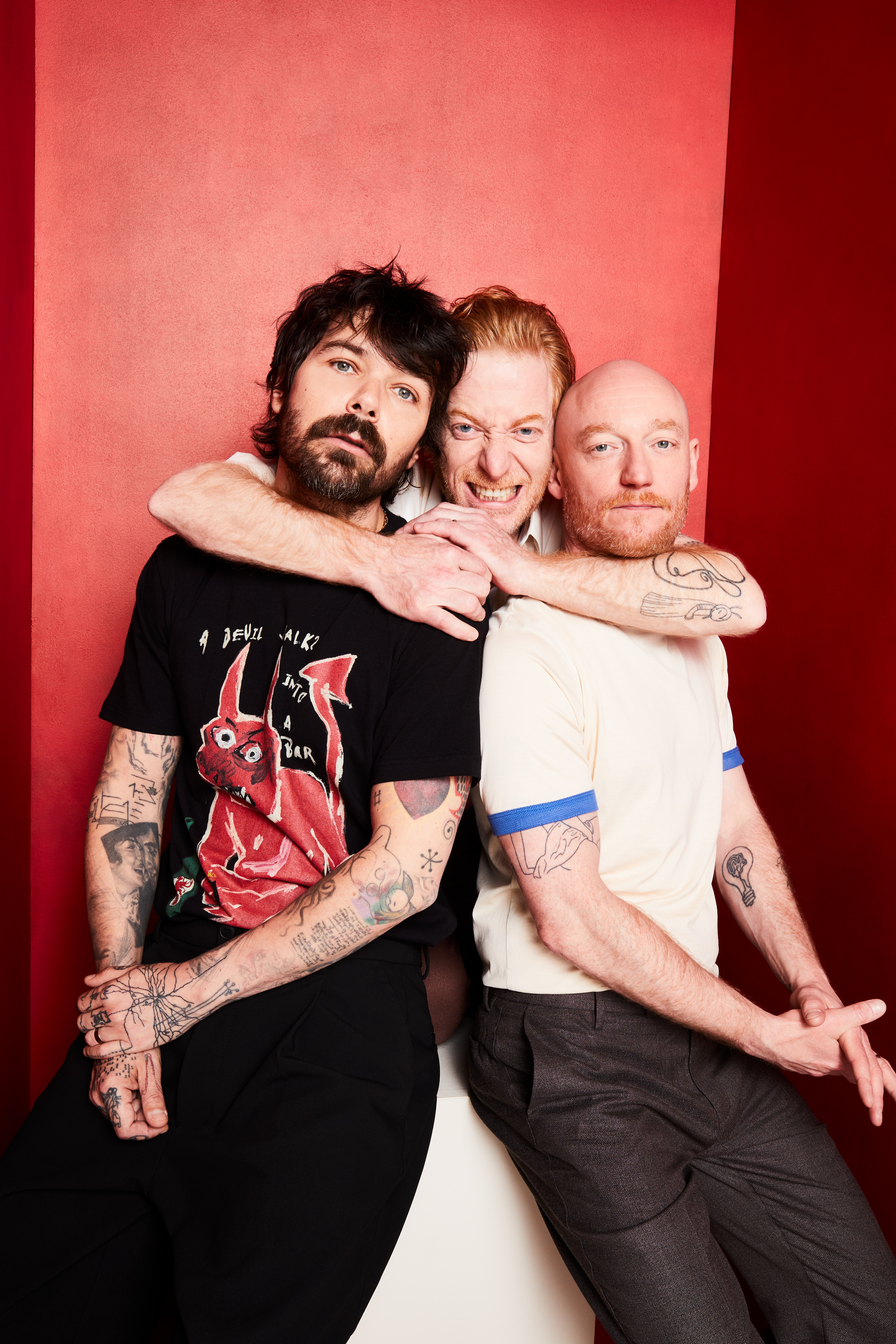 All three Biffy Clyro members posing against a red background