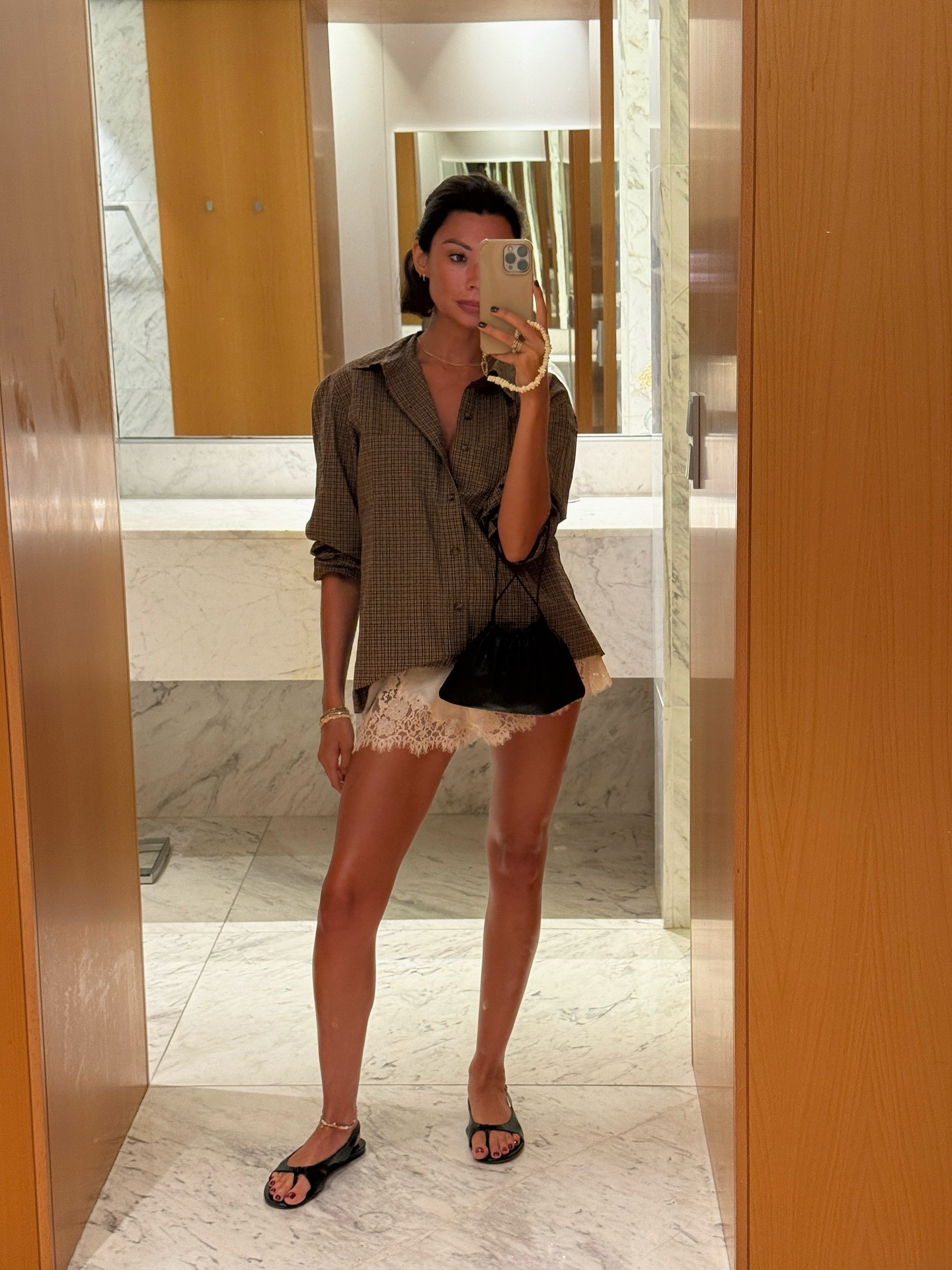 Influencer wearing a button-down shirt, white satin lace-trim shorts, and sandals.