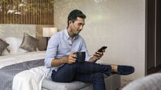 Man sitting on bed using smartphone