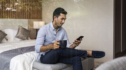 Man sitting on bed using smartphone