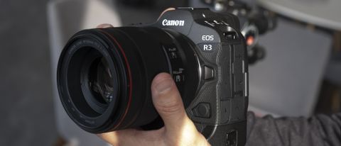 Two hands holding the Canon EOS R3 mirrorless camera