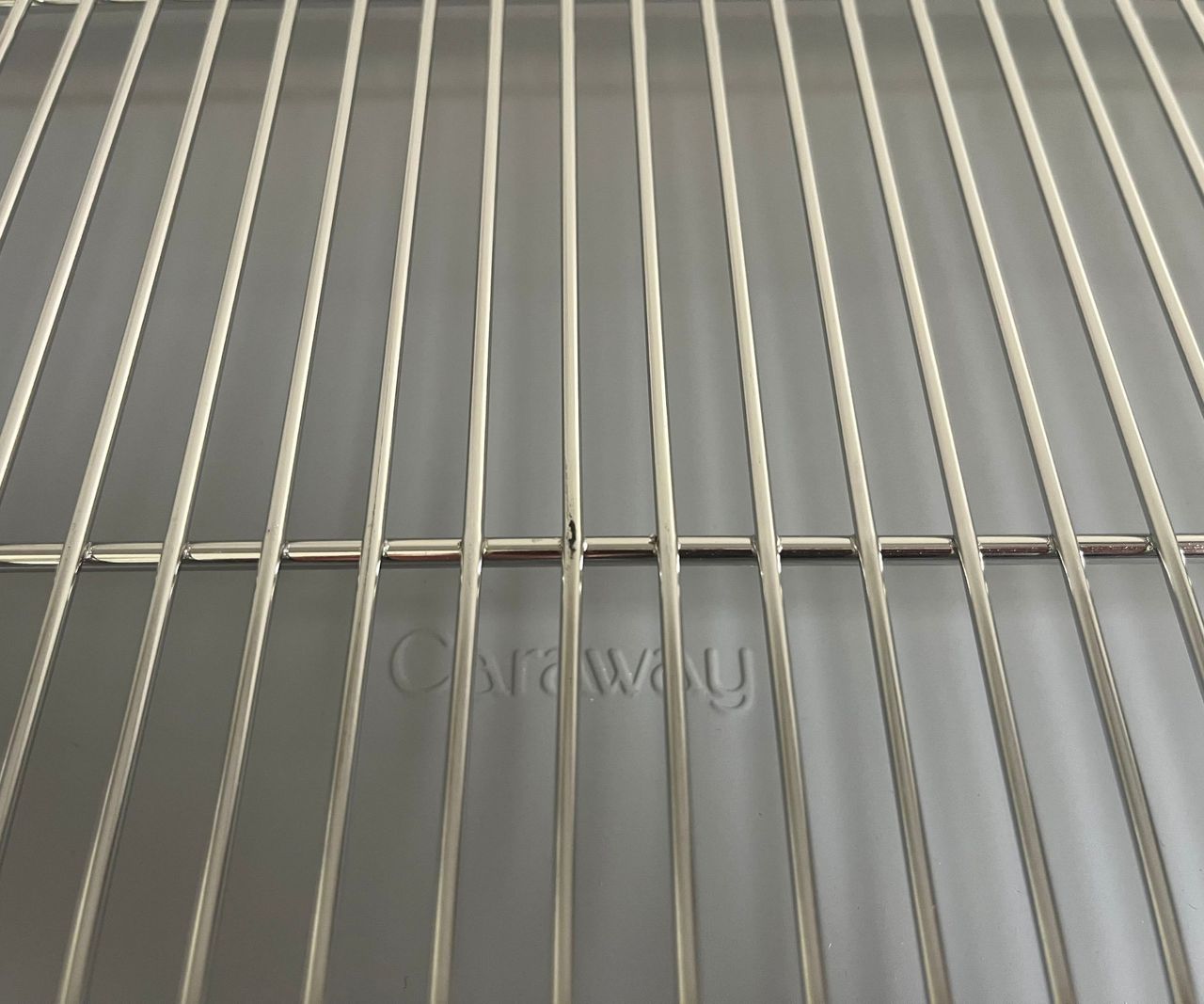 A close up of some scratch marks on a metal wire cooling rack over a grey baking tray