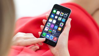 Close-up of an iPhone 6 in the hands of a woman wearing a red dress.