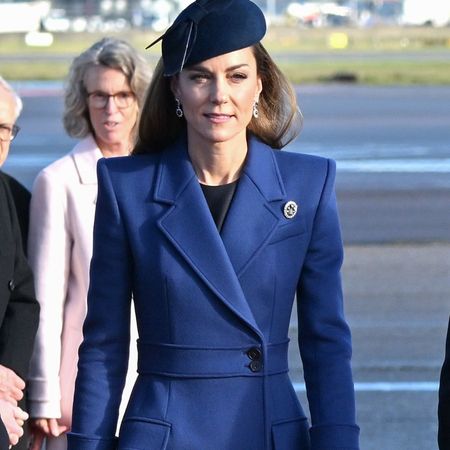 Kate Middleton wears a navy coat with navy suede boots and a navy fascinator.