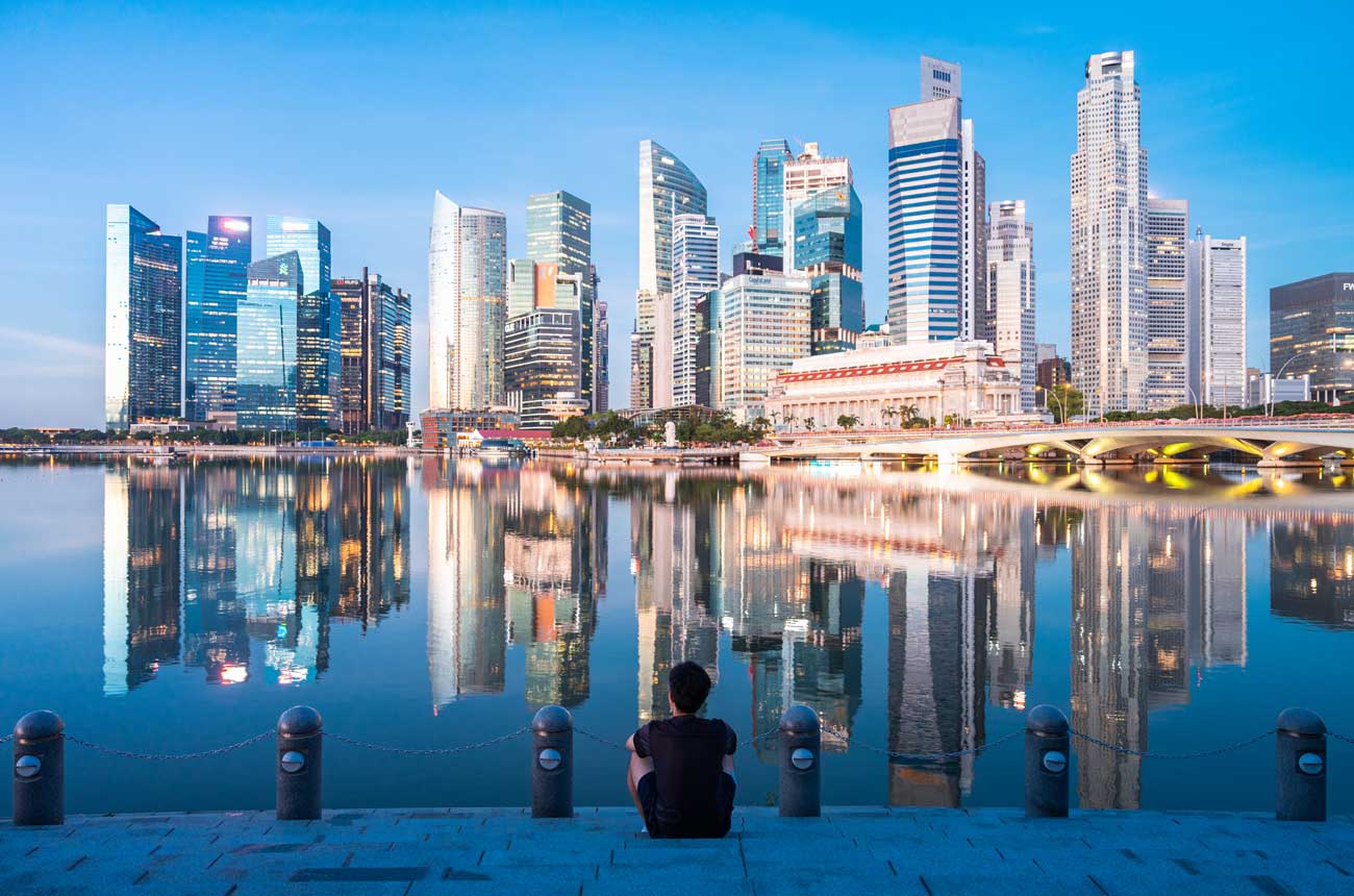 Man sitting on steps looking towards Singapore skyline