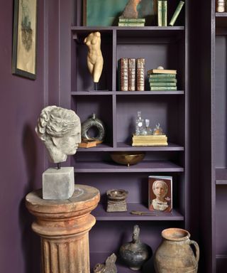 custom built-in shelves painted in dark color with books and keepsakes and classical bust on pedestal
