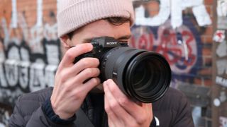 Sony a1 II camera with a Sony FE 28-70mm f/2 GM lens attached held up to a person's face