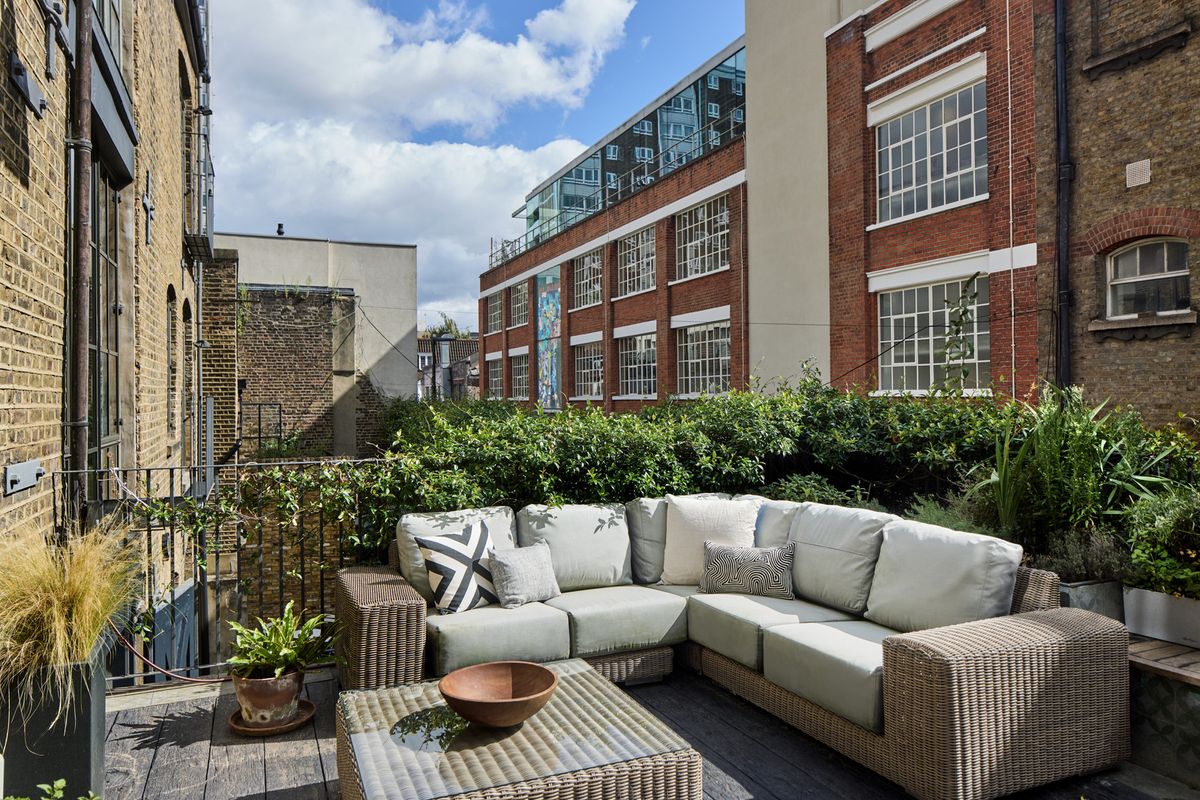 A lounger on a balcony with plants on the handrails