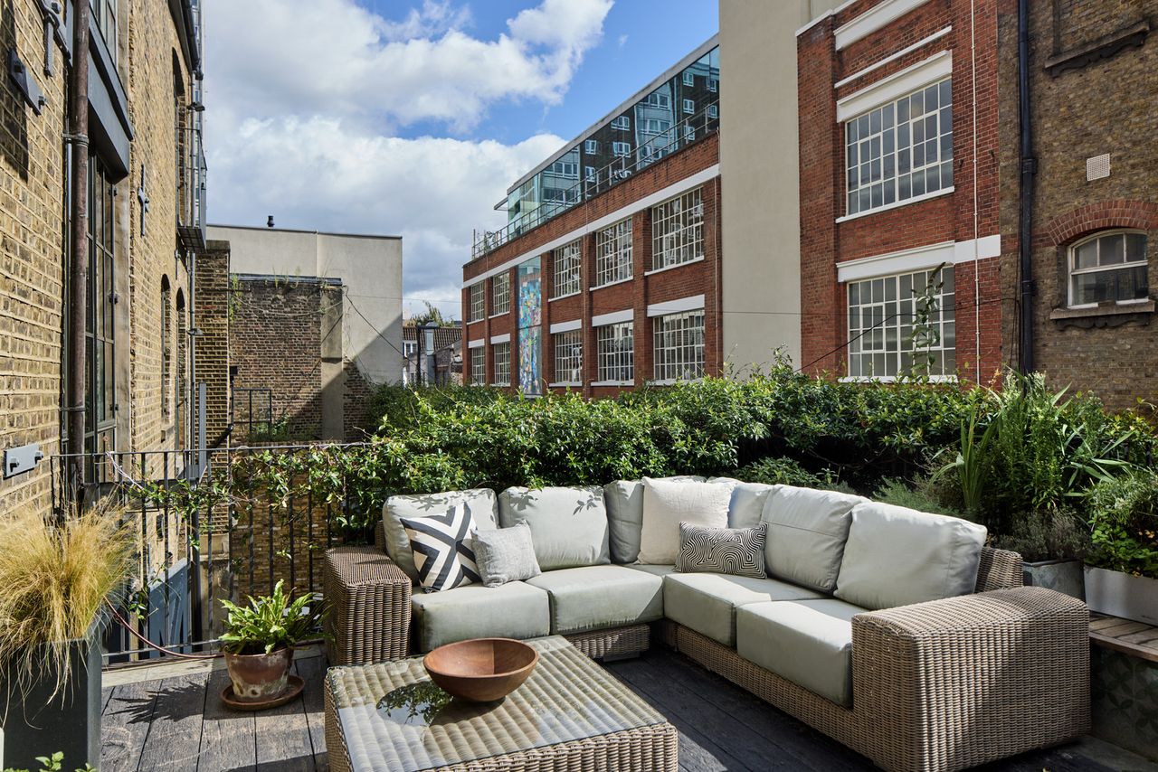 A lounger on a balcony with plants on the handrails
