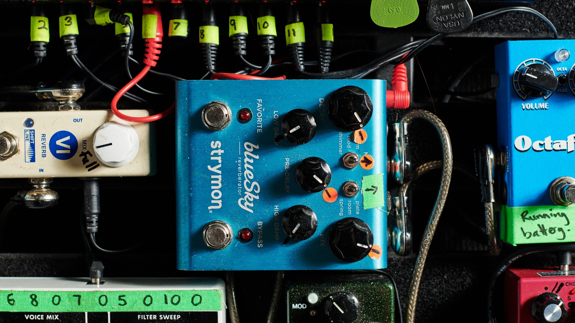 A Strymon guitar pedal on a busy pedalboard with lots of patch cables