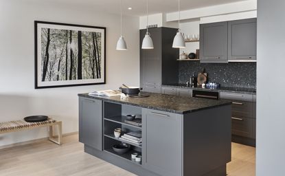A kitchen with black cabinetry and marble countertops