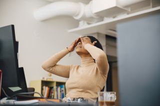 woman touching eyelids at desk