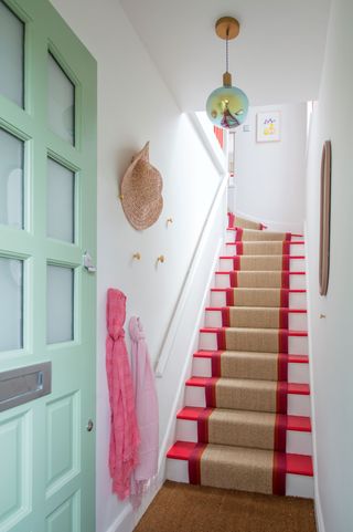 The hallway is led through a lime green door and the stair carpet is bright red with brown hints through the middle