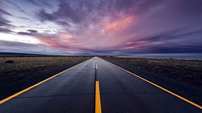 Straight, flat road running through the countryside at sunset