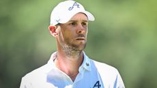 Thomas Pieters from the chest up wearing a white polo shirt and white cap during a LIV Golf tournament