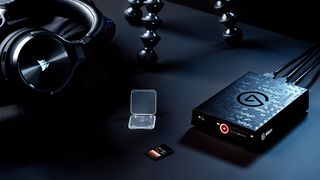 Elgato 4K60 S+ capture card on a black table with headphones and Gorillapod